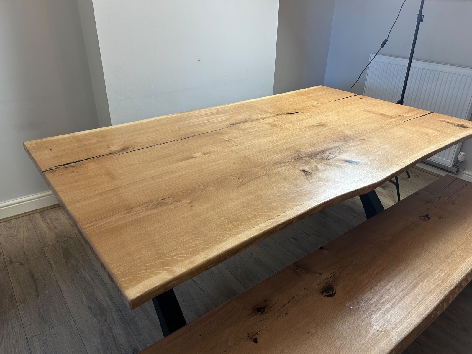 The oak tabletop with the matching bench beneath it, grain and knots visible across the surface