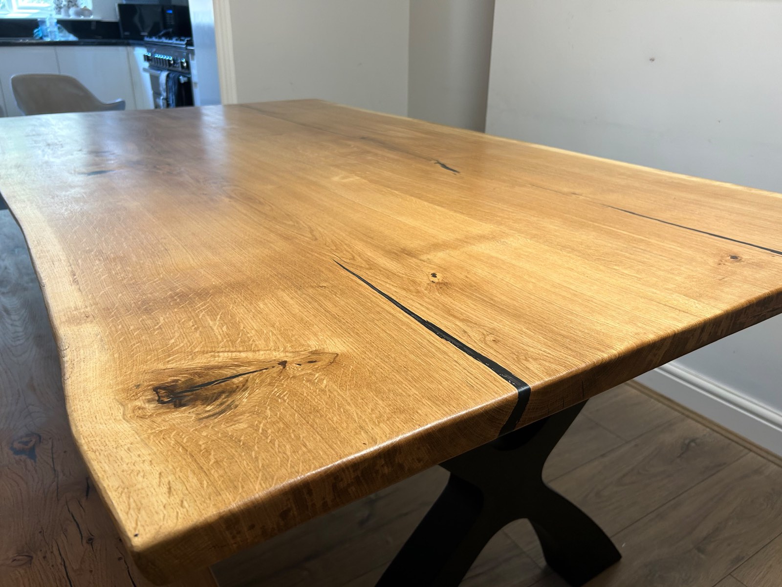 The corner of the oak top showing the eased edge, live edge profile and the leg below