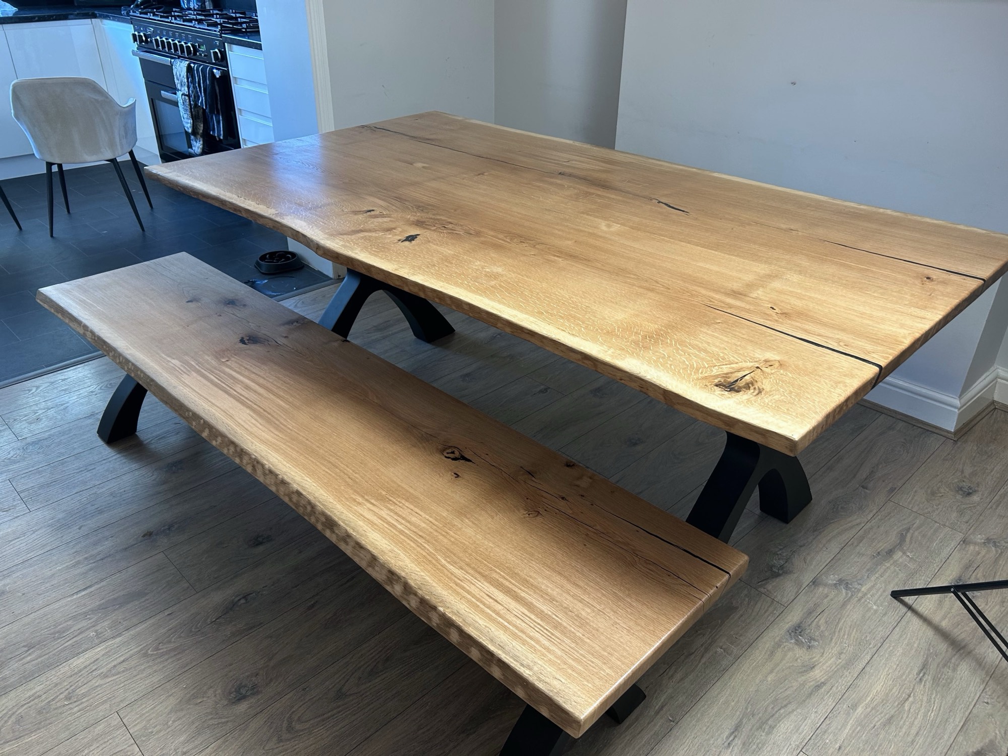 200cm solid French oak dining table with natural finish, live edge and black Designer X legs, with a matching bench, in a customer's kitchen in Wickford