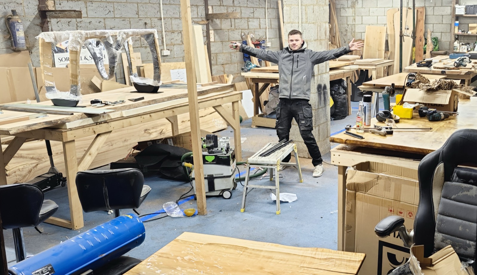 The Timber Row workshop floor in Wickford — benches of solid oak slabs and tables mid-build
