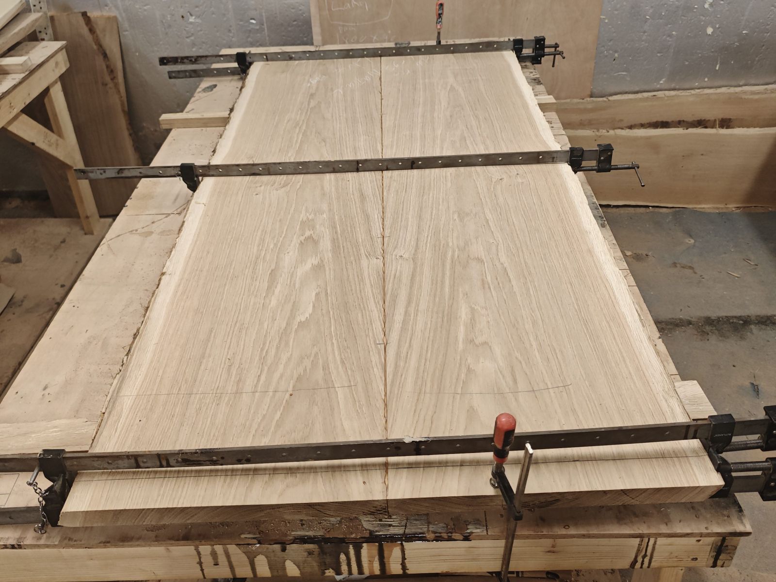 Two French oak slabs in sash clamps on the bench while the centre joint sets