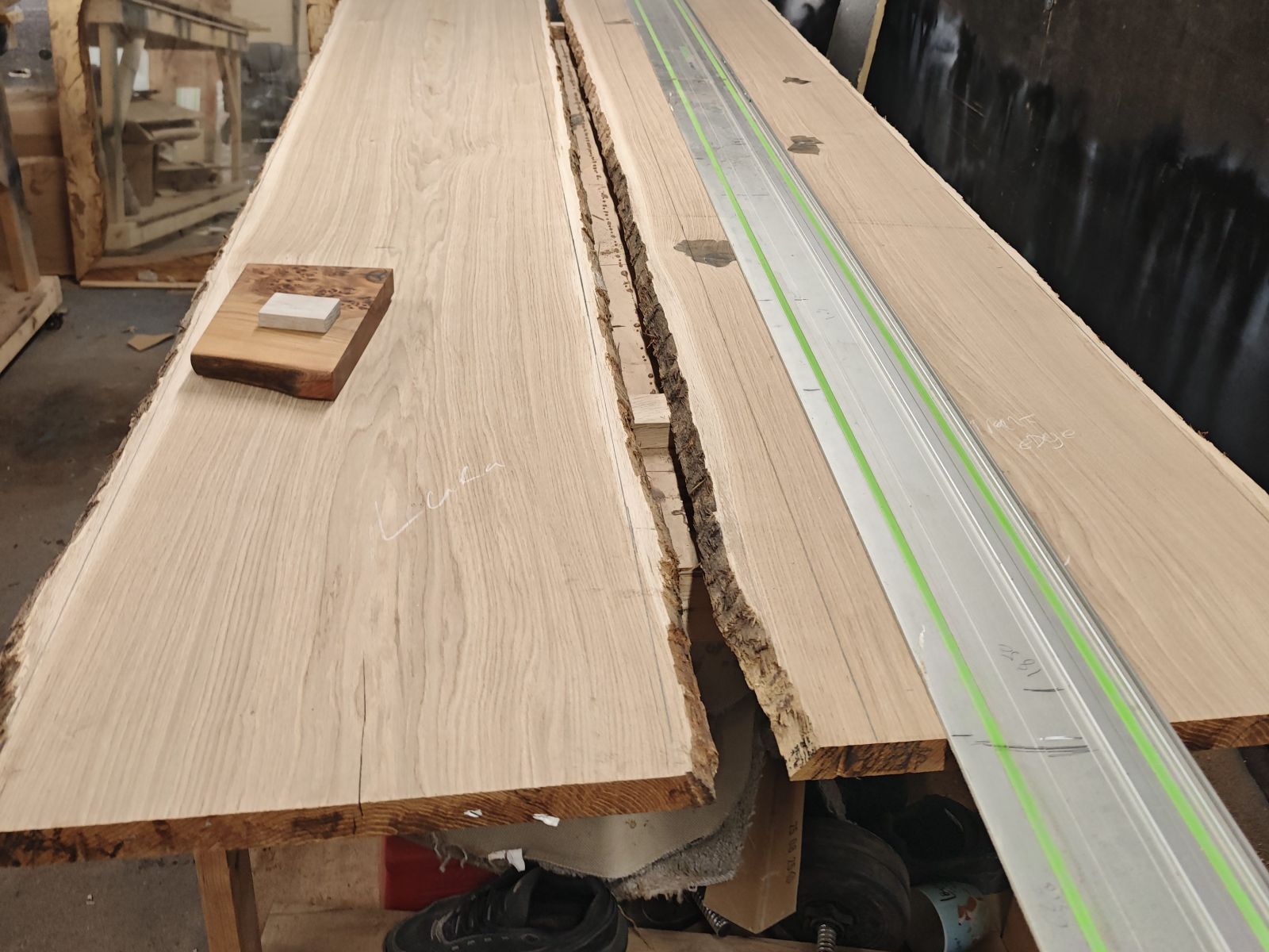Live-edge French oak boards on the bench with the track-saw rail laid along them.