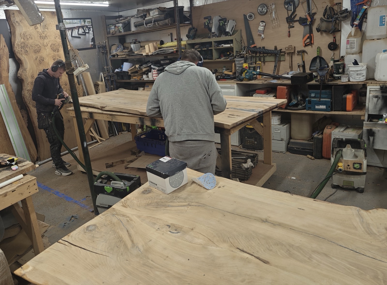 Hand-sanding solid French oak tabletops on the benches in the Wickford workshop